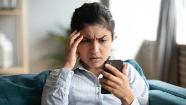 Woman upset by numerous collection calls looks at phone in frustration