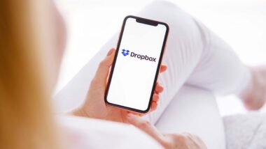 Woman holding a smartphone with the Dropbox logo displayed, representing the Dropbox data breach class action.