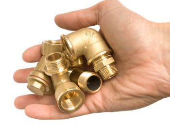 A hand holds brass pipe fittings - Brass Pipe Fittings Lawsuit - uponor class action settlement - brass plumbing products