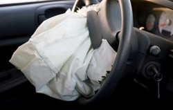 A deflated airbag hangs from a steering wheel - honda class action - takata - air bag settlement - auto air bags