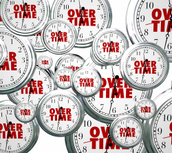 Overtime word on clocks flying by to illustrate time passing as you perform extra or additional work late at your job