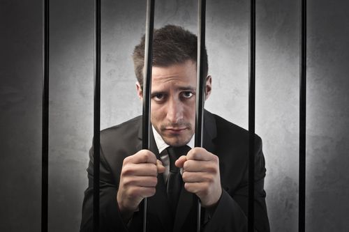 Businessman behind bars feeling guilty