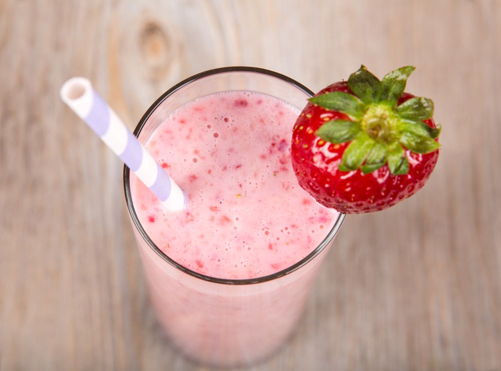 Strawberry healthy milkshake drink. On wooden background.