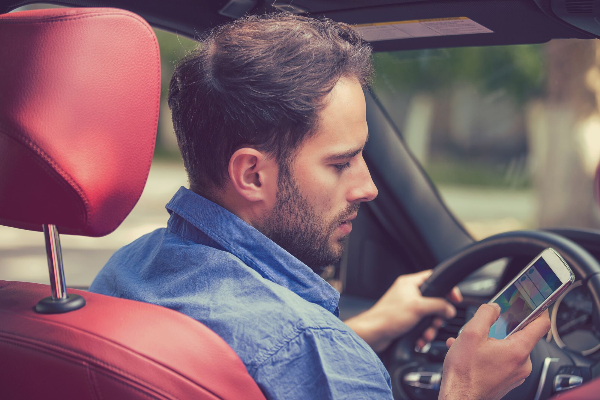 Man using cell phone texting while driving. Risky, reckless driver concept
