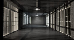 A corridor in a prison at night showing jail cells illuminted by various ominous lights