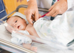 Closeup of doctor's hands examining newborn babygirl in hospital