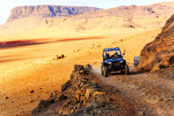 Merzouga, Morocco - Feb 21, 2016: blue Polaris RZR 800 crossing a mountain road in the Moroccan desert near Merzouga. Merzouga is famous for its dunes, the highest in Morocco.
