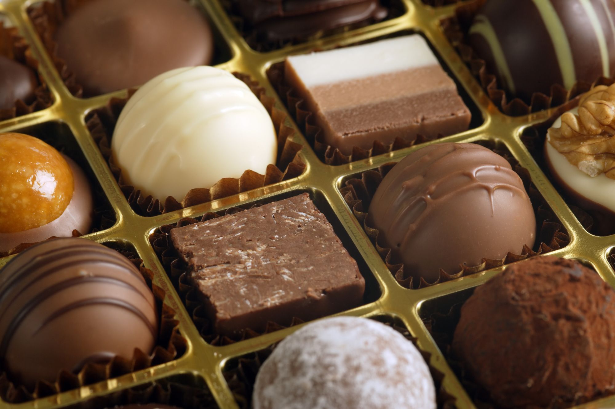 A small assortment of chocolate truffles and pralines in a box. Very Shallow depth of field, focusing across the middle.