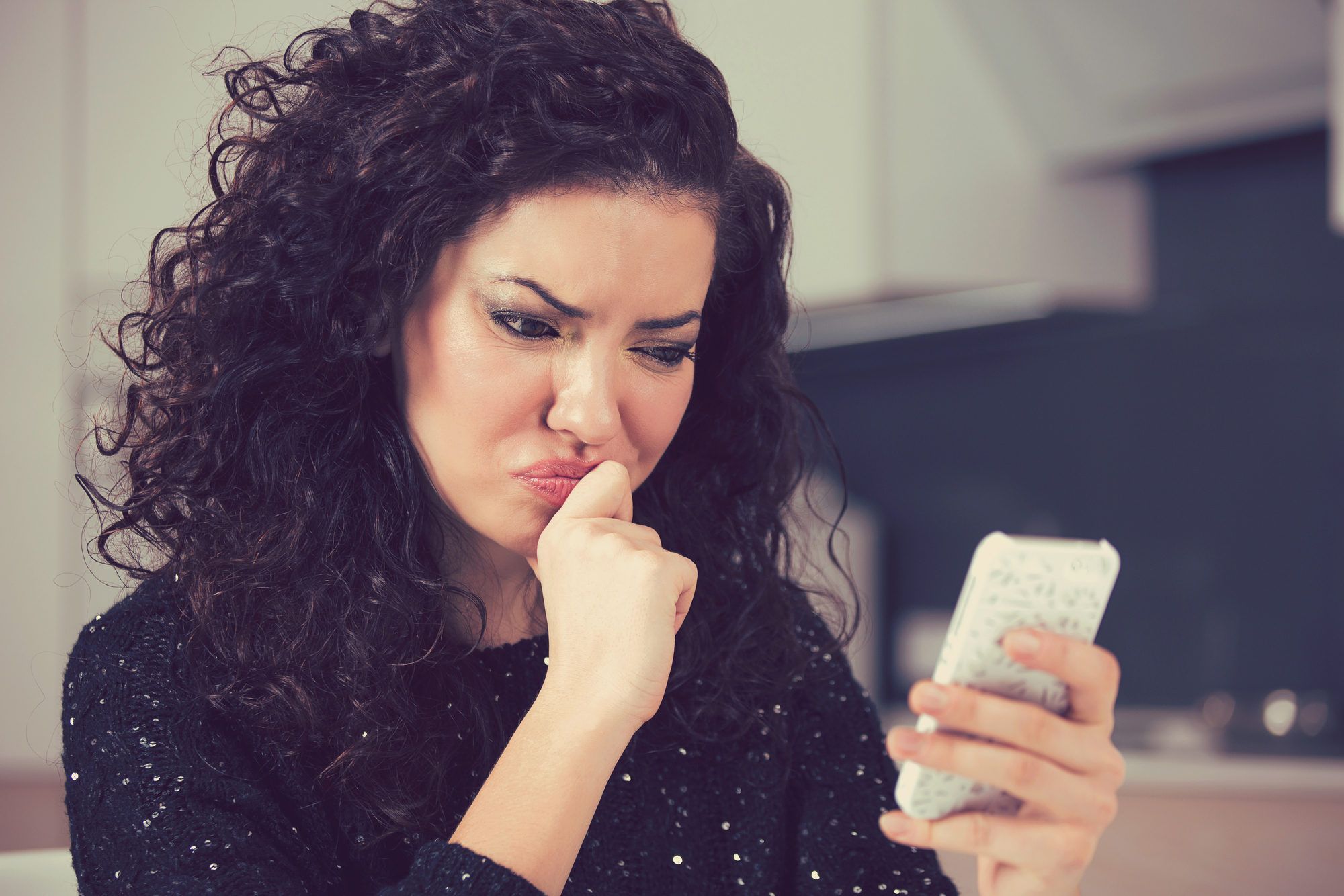 Upset confused young woman suing mobile phone reading text message