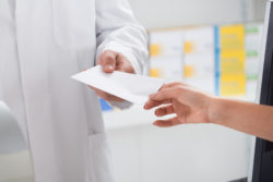 Cropped image of woman giving prescription paper to pharmacist in store