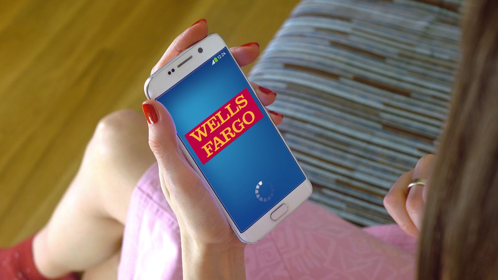 Young woman holding a cell phone with loading Wells Fargo mobile app. Conceptual editorial image