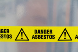 Danger Asbestos yellow warning tape close up - zonolite insulation - vermiculite