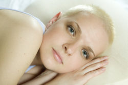 thoughtful blond bald woman lying on the bed
