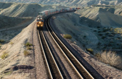 A frieght train rounds a bend in the aride California desert in late afternoon.
