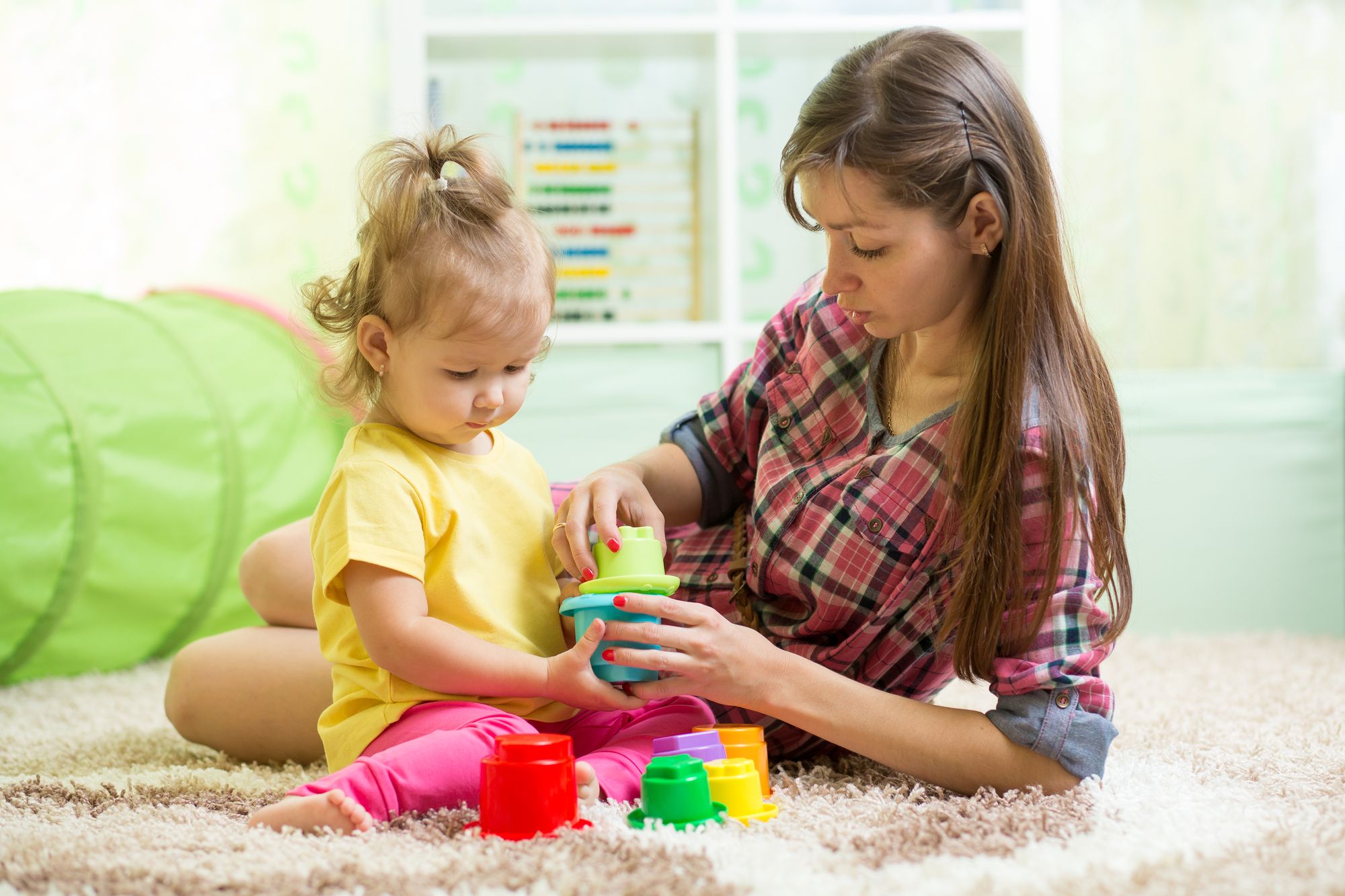 babysitter with kid girl playing in nursery