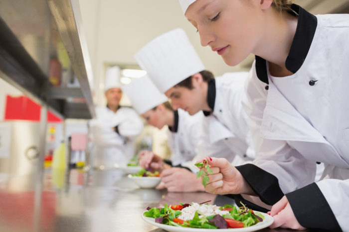 Chef finishing her salad in culinary class in kitchen