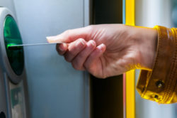 woman hand inserting credit card to ATM. Hand inserting ATM card into bank machine to withdraw money. Young Woman using Bank ATM cash machine on the street