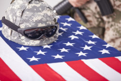 Military funeral - helmet on the american flag and soldier in the background