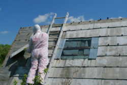 Asbestos removal worker. Dangerous waste disposal - professional works with old architecture.