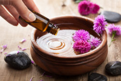 essential oils being dropped into a bowl with flowers