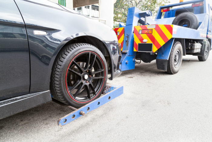 Low view of a car being loaded onto a tow truck - American Credit Acceptance settlement