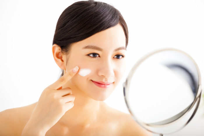 anti-aging facial cream being applied on woman's face