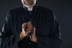 A priest holds a rosary.