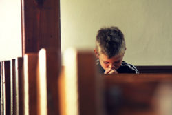 A boy is praying in a church.