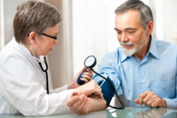 A doctor takes a man's blood pressure.
