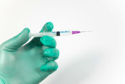 A gloved hand holds a syringe
