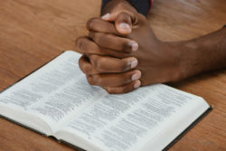 Hands folded in prayer over an open bible