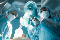 A surgeon applies an oxygen mask