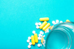 White and yellow antibiotic pills on blue background