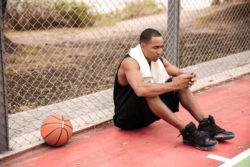 A man gets a text message at a basketball court.
