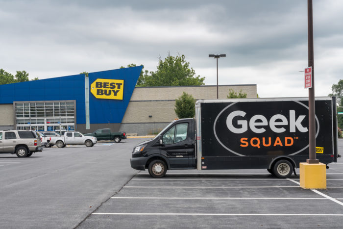 best buy retail location parking lot with a geek squad branded vehicle parked outside