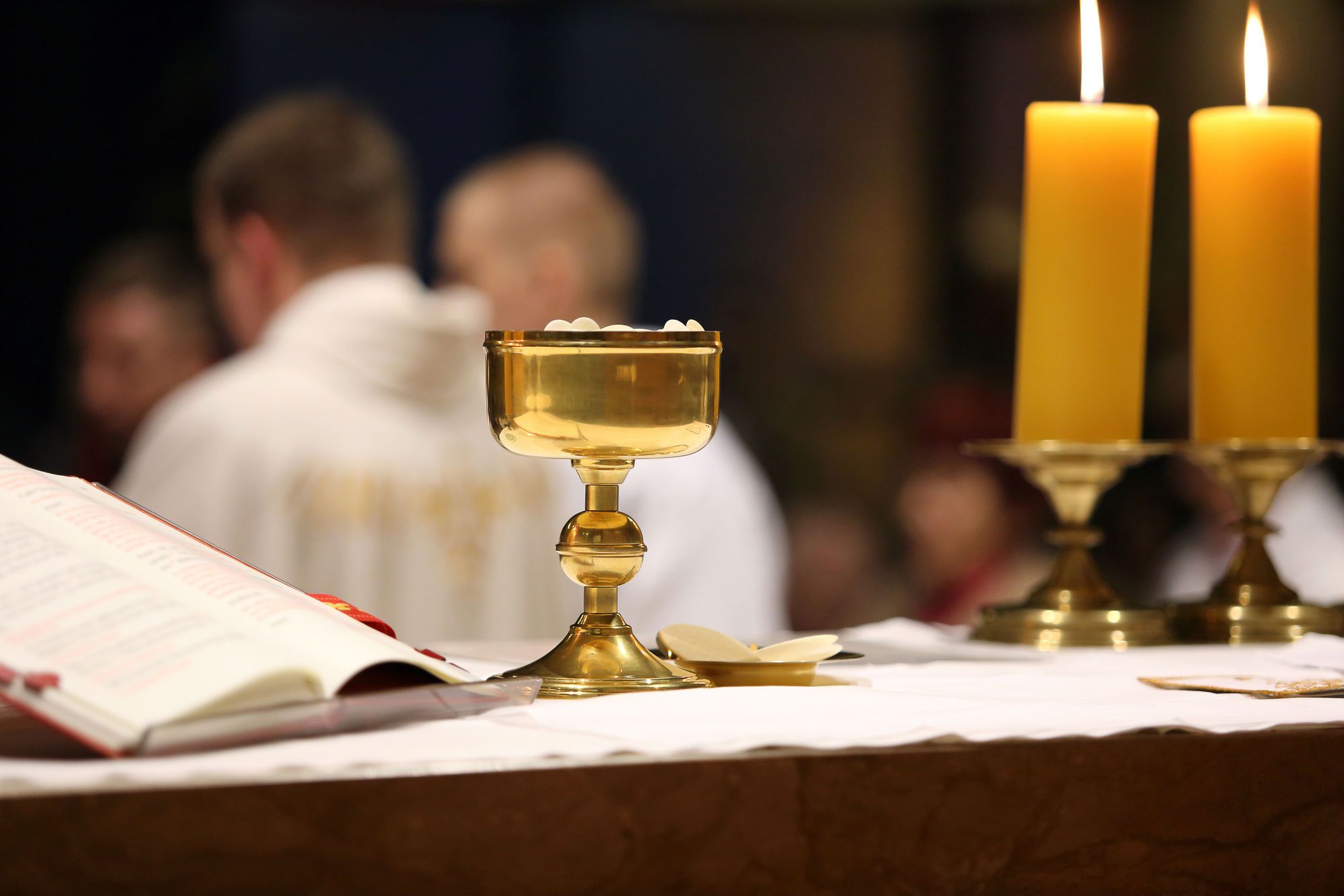 A chalice and two candles sit on a church altar.