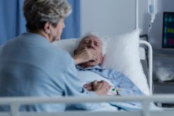 Elderly man coughing in bed in the hospital