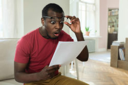 A man looks shocked while he reads his bank statement.