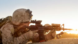 A marine aims a rifle in the desert.