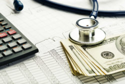 Medical bill with cash, calculator, stethoscope