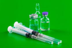 Syringes and vials on a green background.