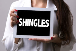 Woman holding sign saying shingles