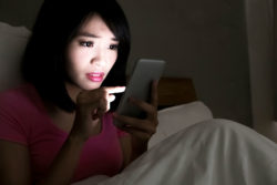 A woman looks distressed while using her smartphone.