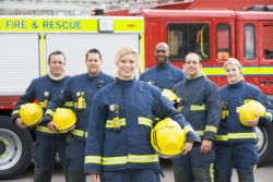 Firefighters stand next to a fire engine.