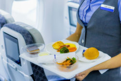 A flight attendant serves a meal.