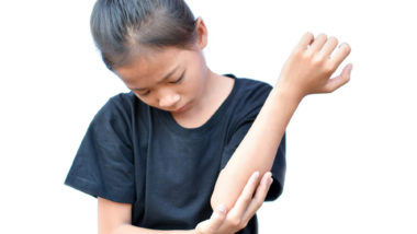 A girl scratches her elbow.