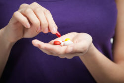 A woman holds a handful of supplements.