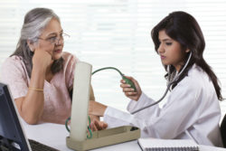 A doctor checks a woman's blood pressure.