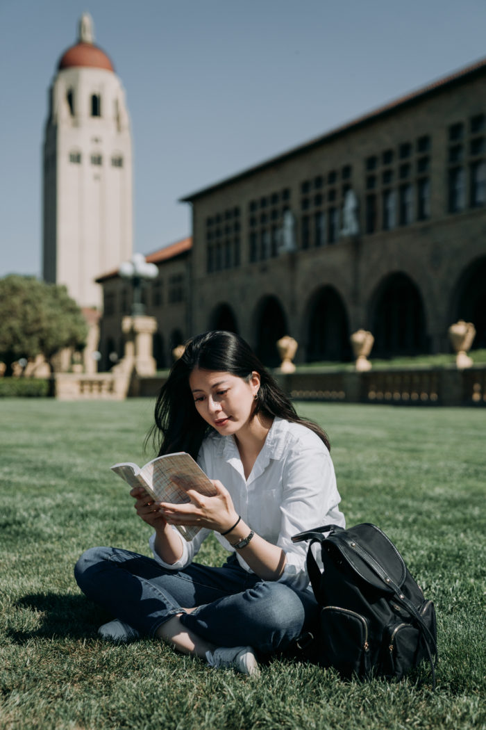 student sitting on the grass reading a book at Stanford University
