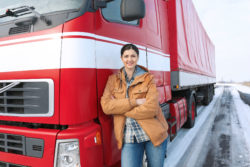A woman stands next to a truck.